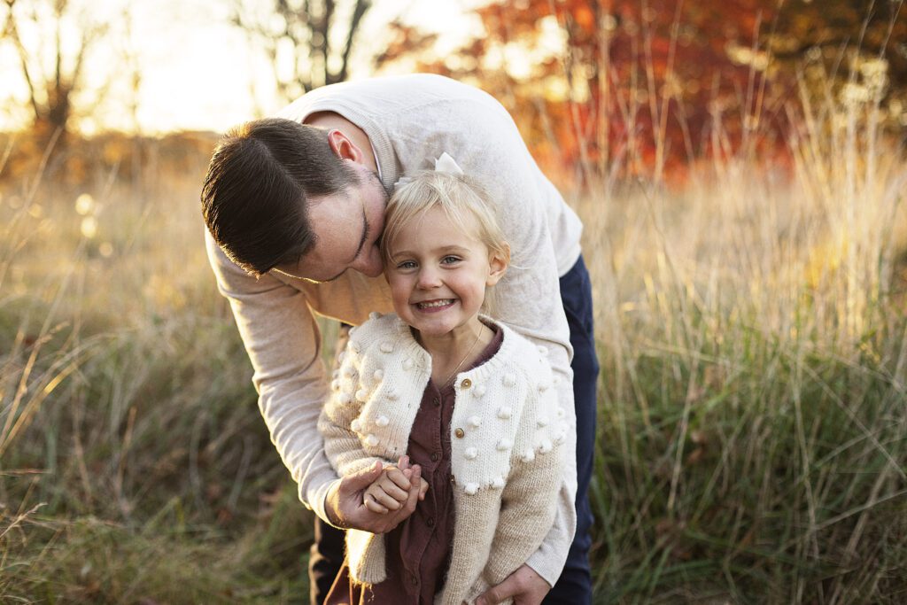 dad hugging daughter in a field during a baltimore family photo session