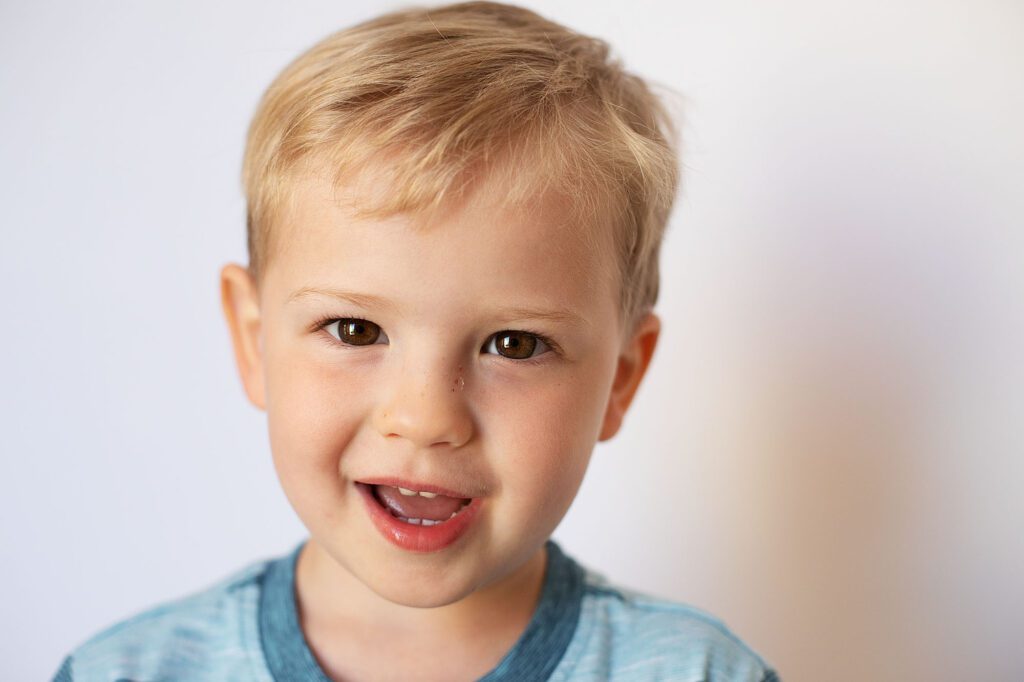 boy standing against white backdrop smiling at annapolis preschool photographer