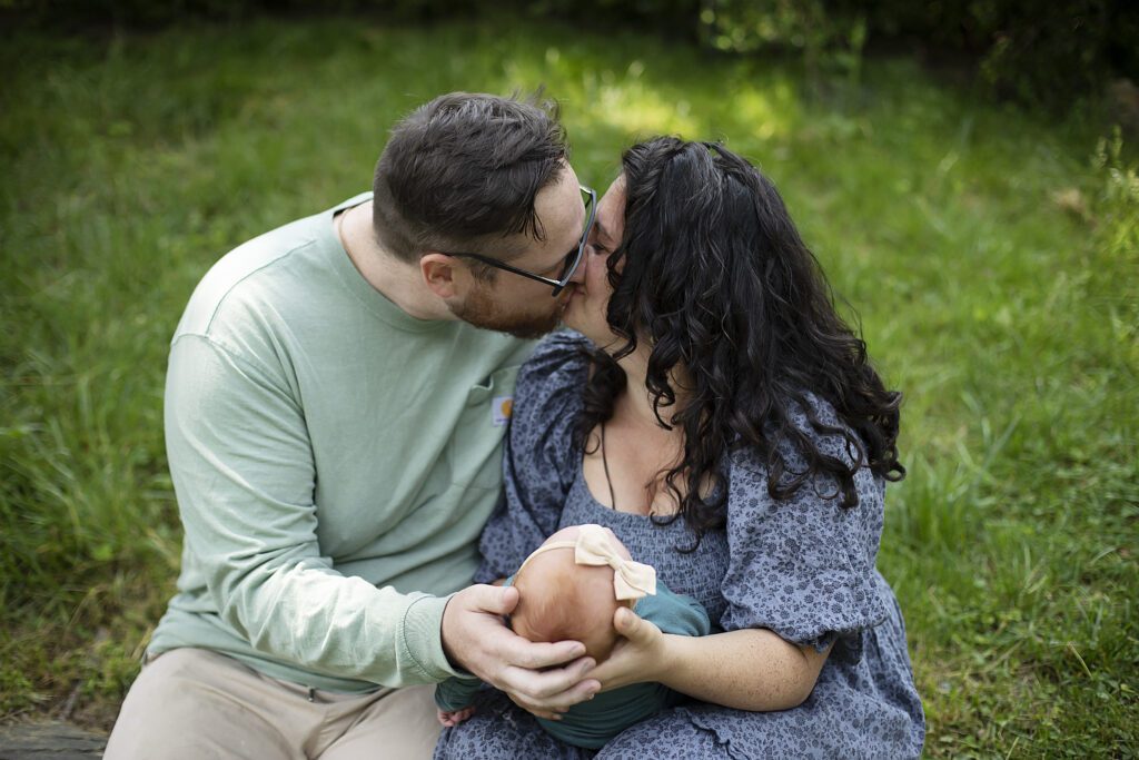 mom and dad embracing during backyard newborn session in baltimore