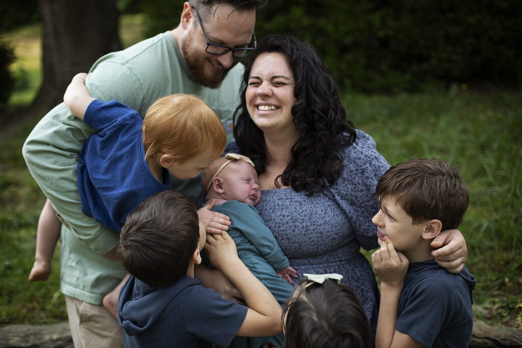 family embracing and smiling in their backyard during in home newborn session in baltimore