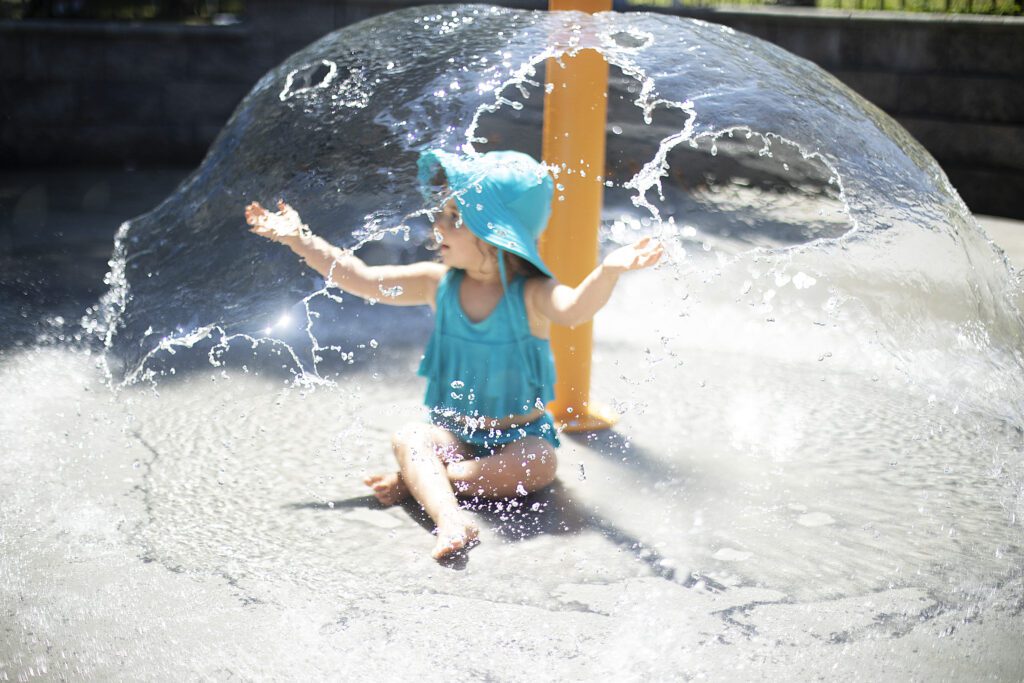 toddler girl playing in water at best splash pad in baltimore millard cooper park splash pad