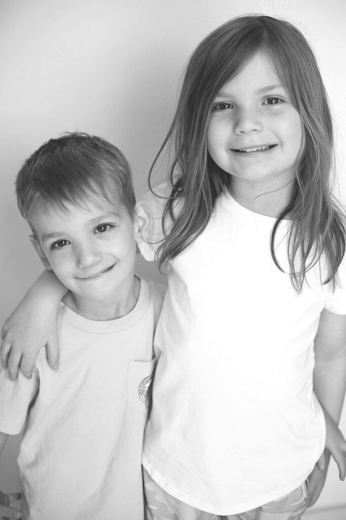 siblings smiling at preschool photographer in columbia md