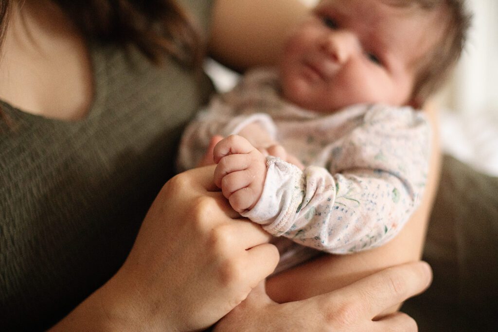 close up of baby holding mom's finger during in home newborn photo session
