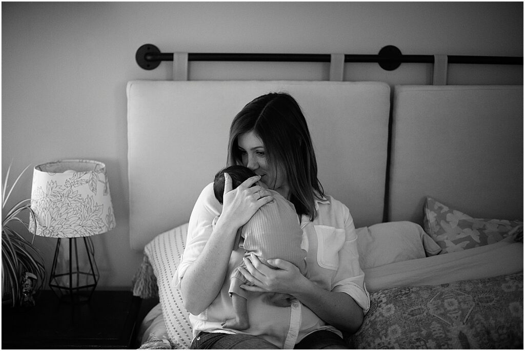 mom kissing newborn during in home baltimore newborn session