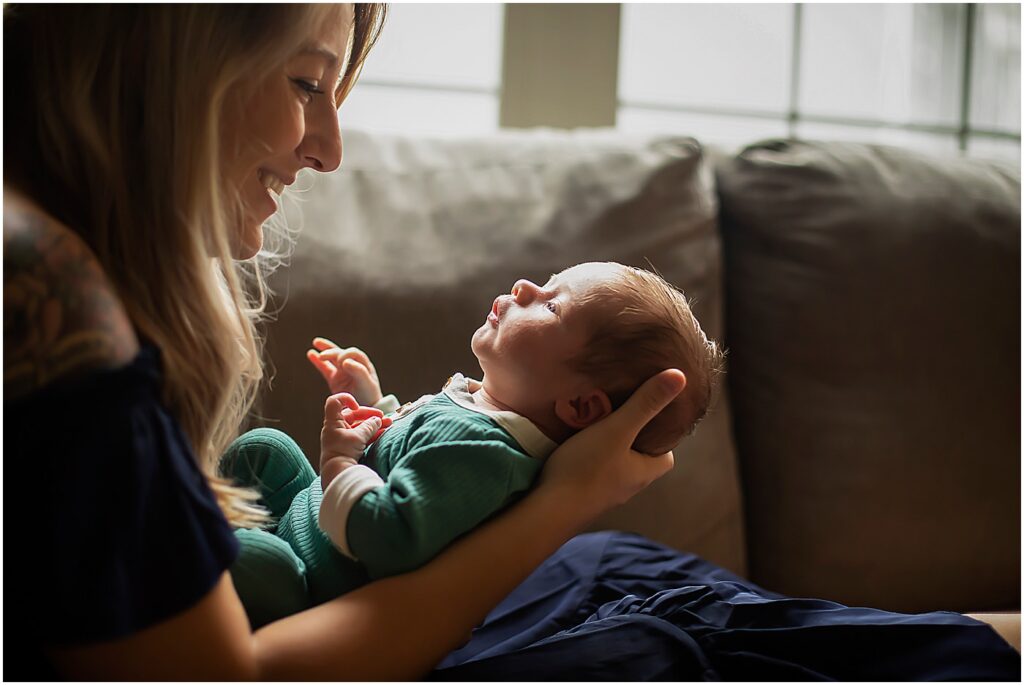 mom and newborn looking at each other on couch during in home newborn session baltimore
