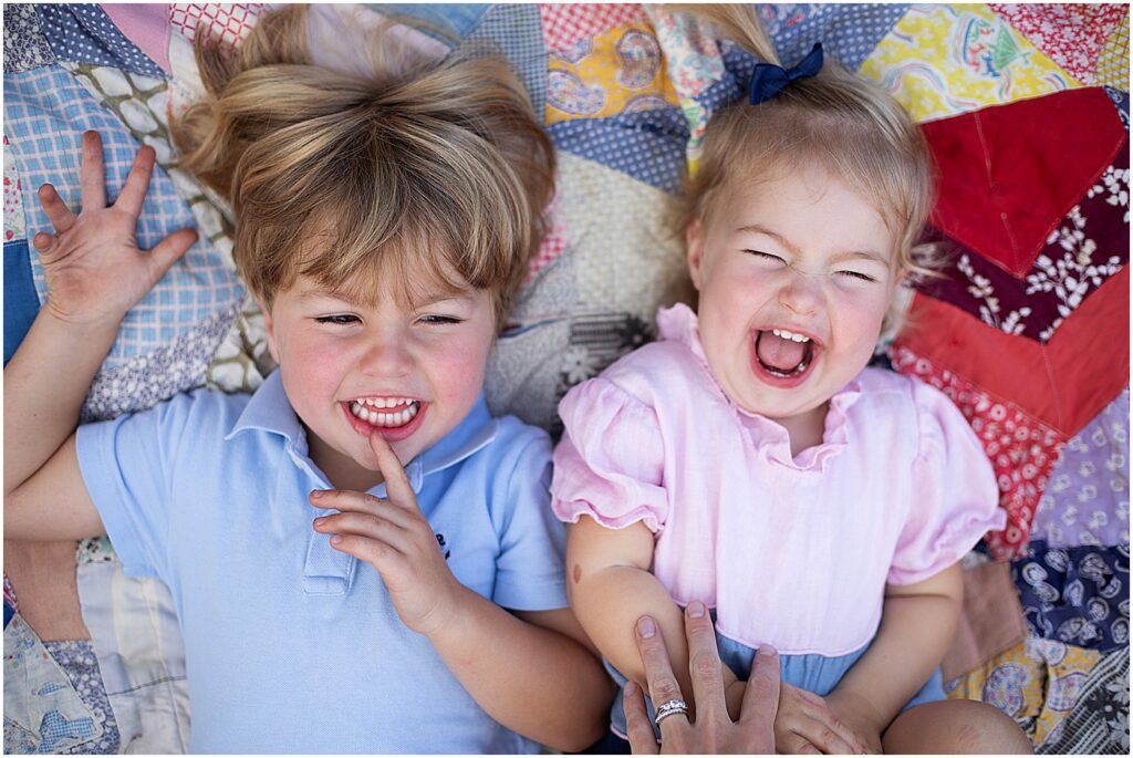 siblings laughing on quilt during best Baltimore family photo session