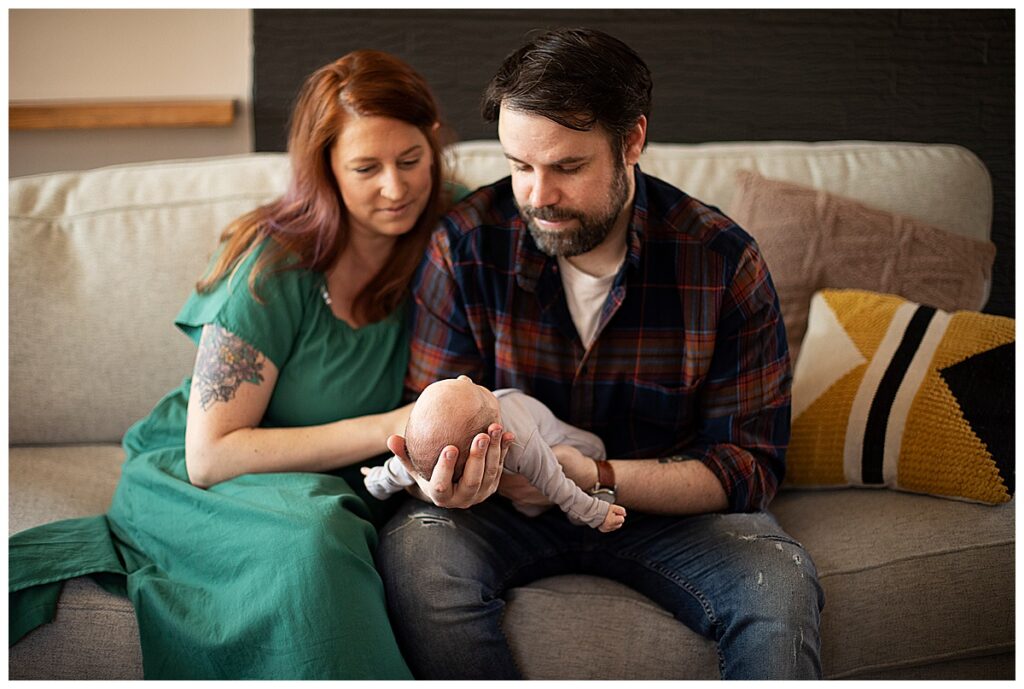 mom and dad sitting on couch with baby