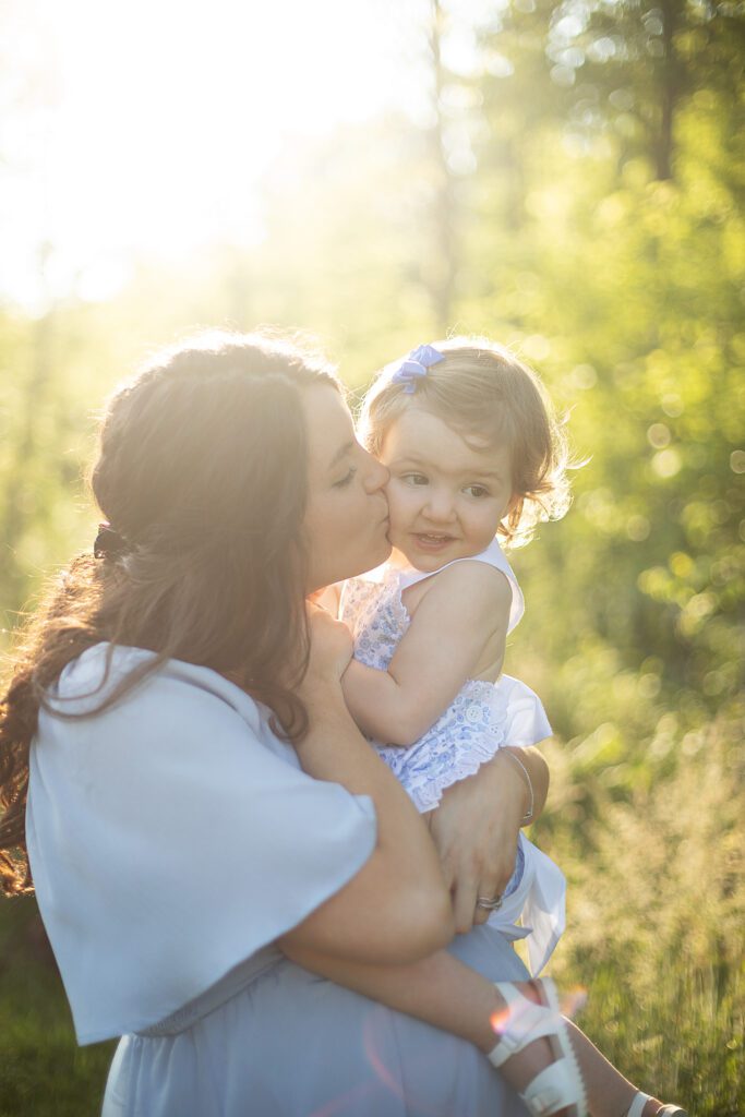 pregnant mom kissing toddler on cheek