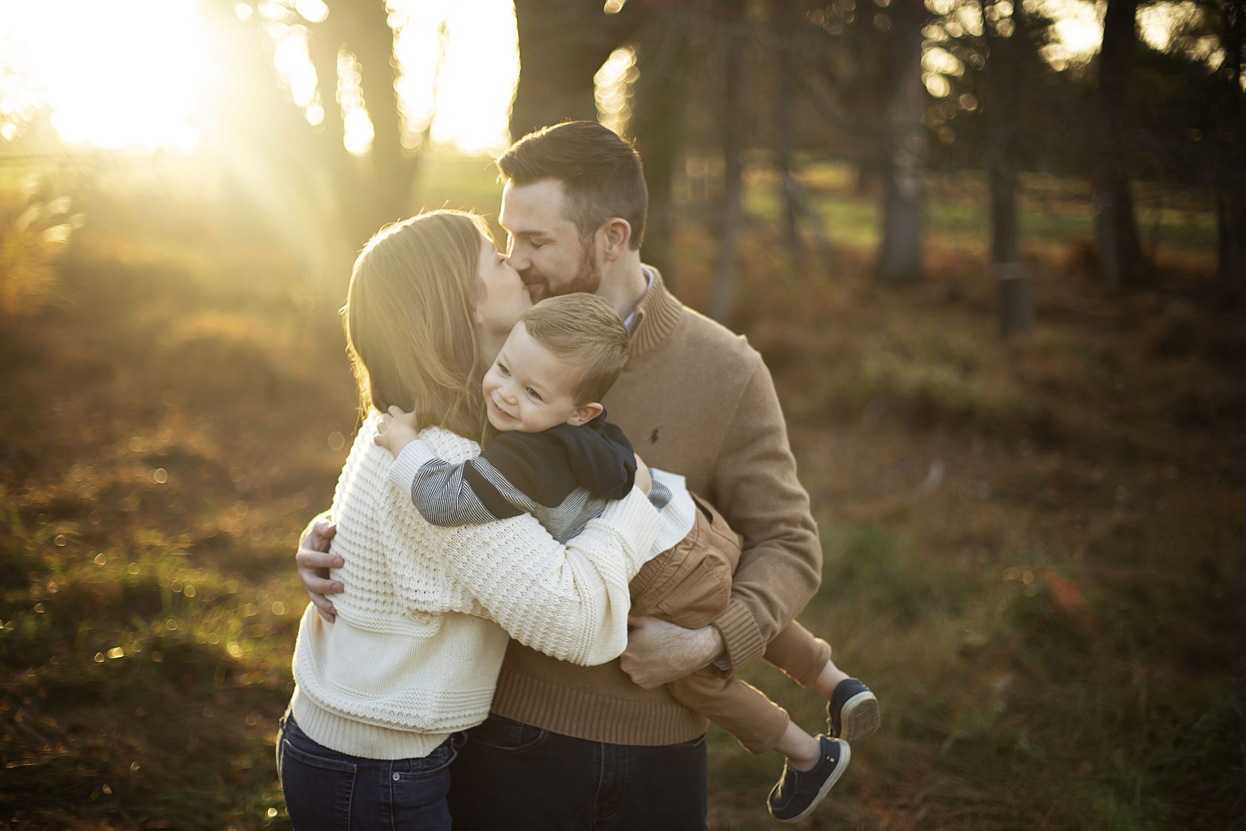Parents cuddling children outdoors in autumn light