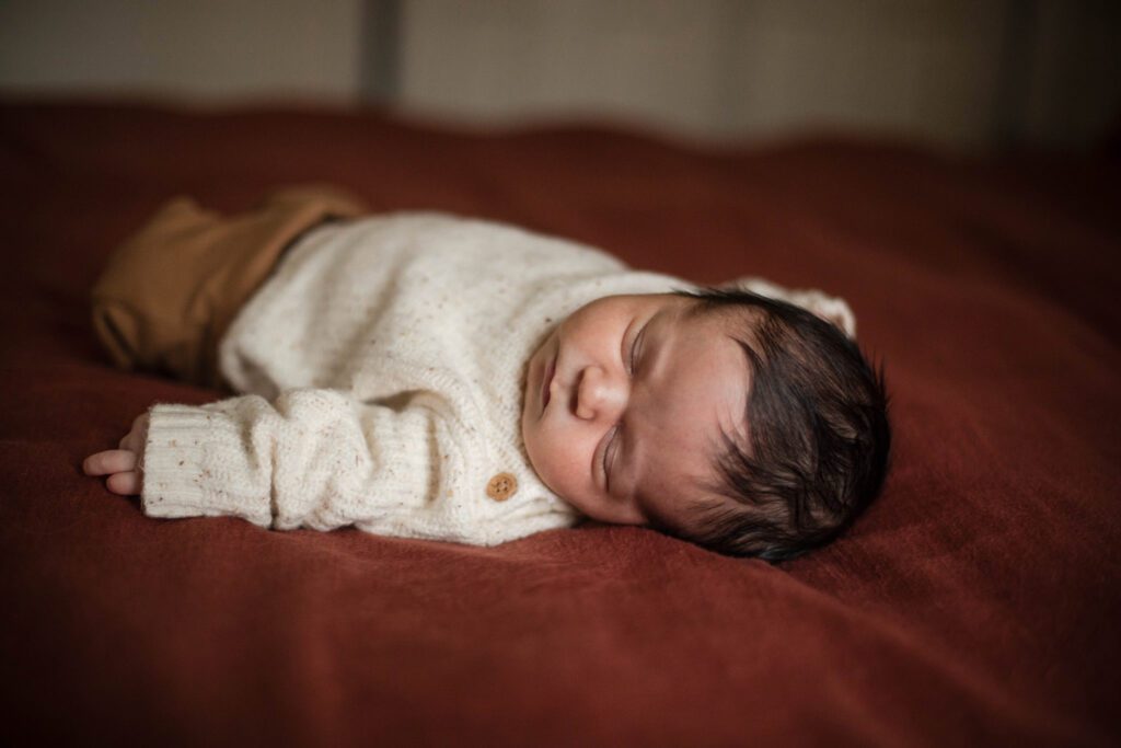 baby boy sleeping on bed during in home newborn session in maryland