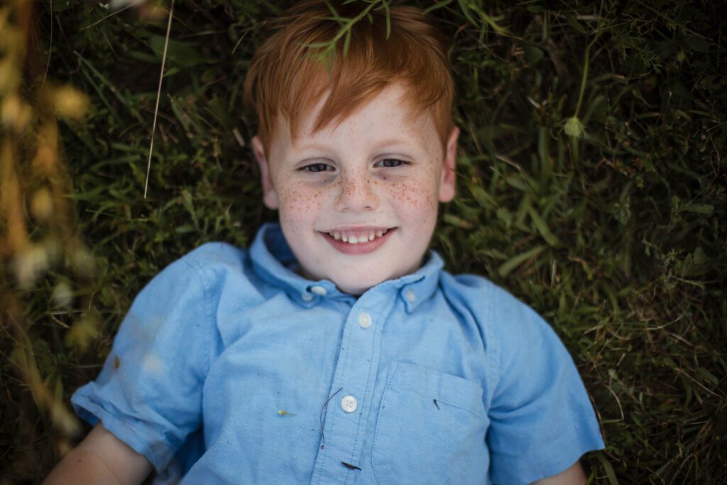 freckle faced boy lying in grass smiling during baltimore family photo session